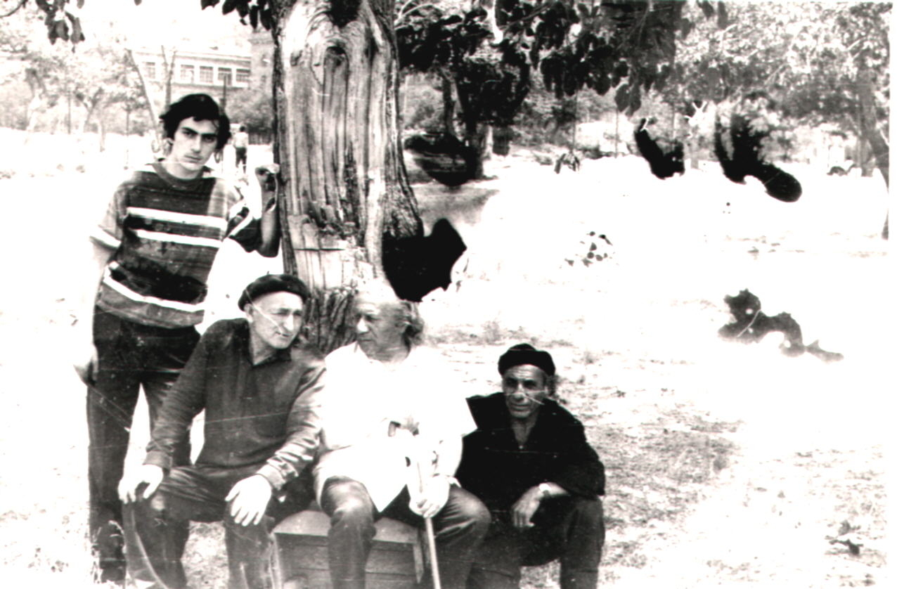 Երվանդ Քոչարը (երրորդը) մի խումբ մարդկանց հետ պուրակում նստած: Ձախից աջ՝ Արմեն Կարախանյան, քարտաշ-արձանագործ Անդրանիկ Բագոյան, չորրորդ անձը դեռևս պարզաբանված չէ, Երևան, 1974